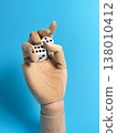 Wooden hand holds two dice against a blue background in a creative setup for games and chance 138010412