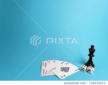 Playing cards and dice on a blue surface along with a chess piece showing a game setup 138010413