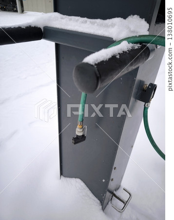 A self-service stand for cyclists with a pump and tools in winter. A self-service stand for cyclists with a pump and tools in winter. 138010695