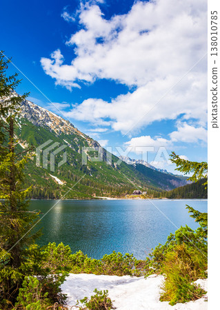 landscape with alpine lake in spring. beautiful view near snow capped rysy peaks. rocks on the foreground. travel background with sky and clouds. spectacular vista on wonderful weather 138010785