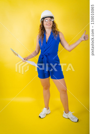 Woman engineer holding blueprints giving thumbs-up 138010865