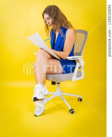 Woman working on documents with pencil sitting office chair Woman working on documents with pencil sitting office chair 138010895