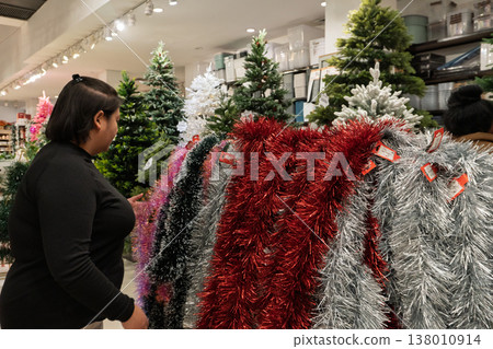 Woman shopping for Christmas garlands in store Woman shopping for Christmas garlands in store 138010914