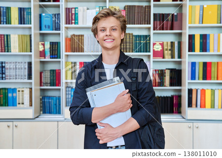 Portrait of smiling teenage student with backpack textbooks in classroom library Portrait of smiling teenage student with backpack textbooks in classroom library 138011010