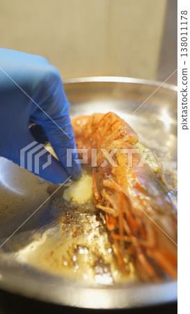 An intimate shot of hand glazing prawn with melted butter before serving An intimate shot of hand glazing prawn with melted butter before serving 138011178