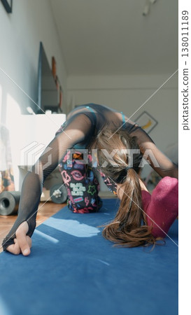 Spirited woman practices backbend exercise comfortably inside her house Spirited woman practices backbend exercise comfortably inside her house 138011189