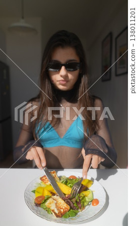 Single woman assembling vivid salad in modern apartment environment 138011201