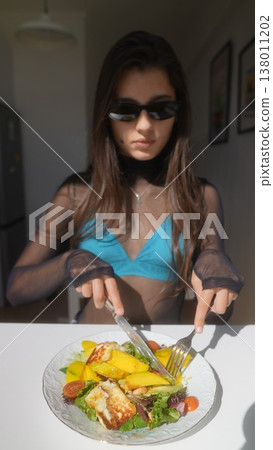 Stylish woman with sunglasses focusing on her meal during peaceful moment 138011202
