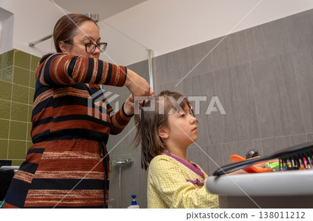 Woman creates neat hairstyle for child after washing before the start of day. Woman creates neat hairstyle for child after washing before the start of day. 138011212