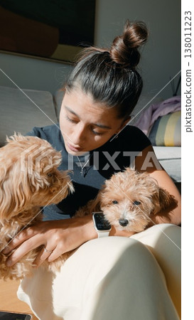 Woman kisses puppy. Woman shares affection with puppy on sofa Woman kisses puppy. Woman shares affection with puppy on sofa 138011223
