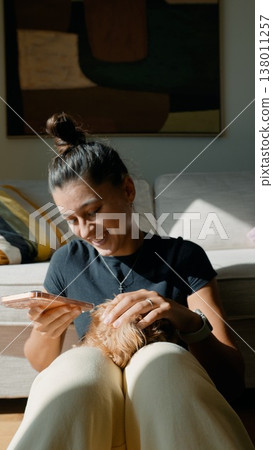 Woman in casual wear shares joyful grooming moment with puppy Woman in casual wear shares joyful grooming moment with puppy 138011257