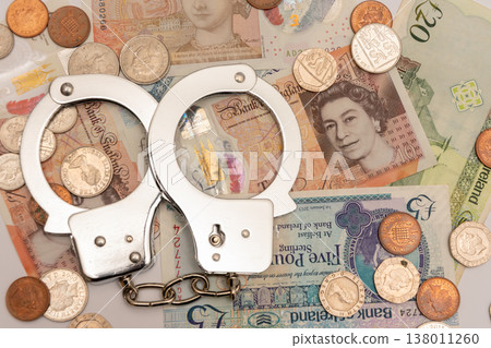 Handcuffs on British pounds symbolizing corruption and financial crime 138011260
