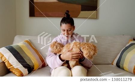 Cheerful woman embraces playful puppy in cozy casual setting 138011279
