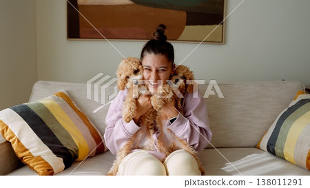 Female individual positioned with small poodle on soft sofa Female individual positioned with small poodle on soft sofa 138011291
