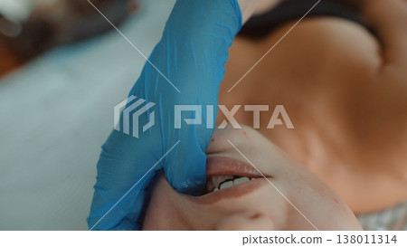 Sterile glove performs gentle pressure near lip and cheek area Sterile glove performs gentle pressure near lip and cheek area 138011314