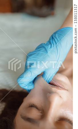 Woman receiving nasal swab while lying on bed with gentle contact Woman receiving nasal swab while lying on bed with gentle contact 138011317