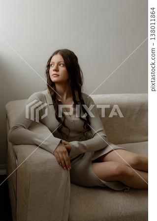Calm Female Figure Seated Comfortably On Beige Sofa In Minimalistic Interior Setting 138011864