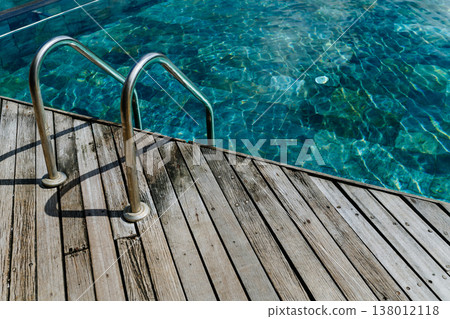 Wooden jetty with metal ladder leading into calm turquoise sea in Mauritius resort. 138012118