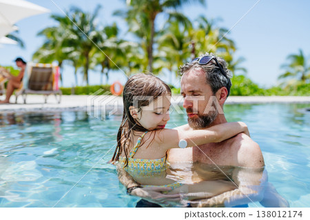 Family playing in tropical resort pool, child with diabetes wears glucose monitor. Family playing in tropical resort pool, child with diabetes wears glucose monitor. 138012174