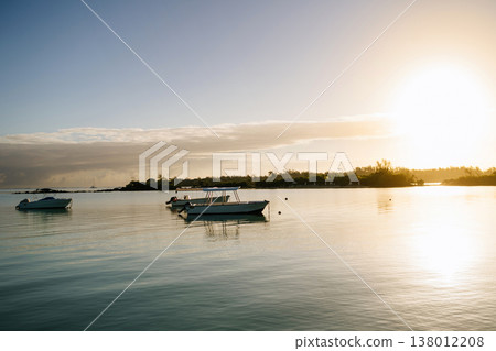 Boats on calm sea at sunset in Mauritius tropical resort with golden light. Boats on calm sea at sunset in Mauritius tropical resort with golden light. 138012208