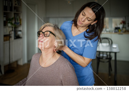 Physiotherapist helping senior woman during rehabilitation exercise at home. 138012258