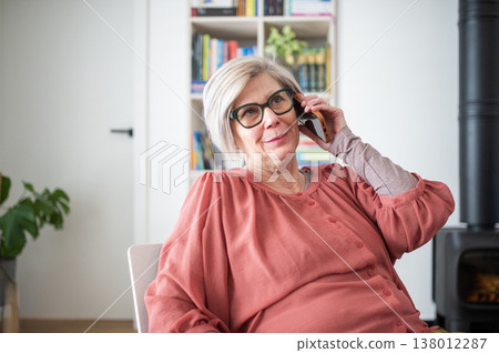 Older woman talking on phone while working from home during retirement. 138012287