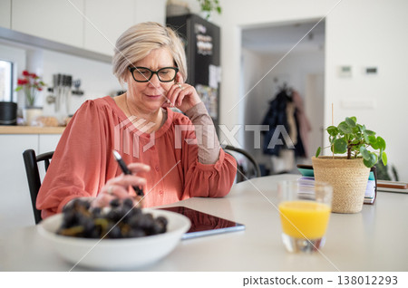Senior woman working on tablet at home office during retirement. Senior woman working on tablet at home office during retirement. 138012293