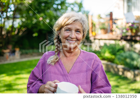 Quiet morning in garden for older woman. Self ritual with coffee. 138012350