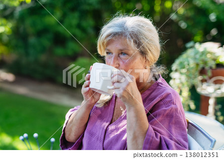 Quiet morning in garden for older woman. Self ritual with coffee. 138012351