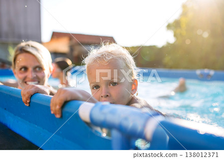 Mother playing with little son in pool. Mother playing with little son in pool. 138012371
