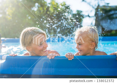 Mother playing with little son in pool. 138012372