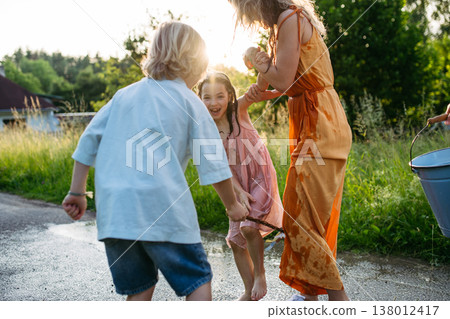 Father and son pouring water on girls during Easter Monday tradition. Father and son pouring water on girls during Easter Monday tradition. 138012417