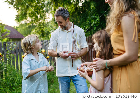 Girl rewarding boy with Easter eggs after Easter Monday whipping tradition. 138012440