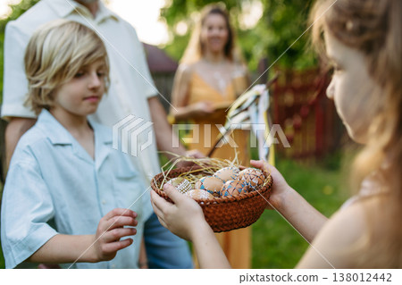 Girl giving decorated Easter eggs to boy after Easter Monday tradition. 138012442