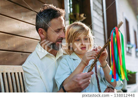 Father and boy braiding easter whip from willow branches. Father and boy braiding easter whip from willow branches. 138012448