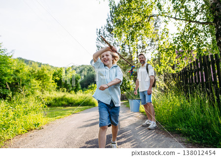 Father and son carrying Easter whip and bucket on Easter Monday tradition. 138012454
