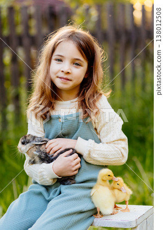 Smiling child playing with baby animals in the garden. 138012508