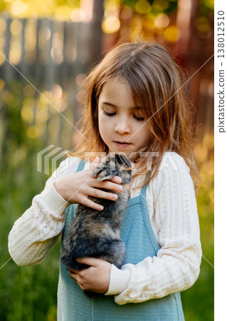 Young girl gently cuddles a fluffy bunny in her arms. Young girl gently cuddles a fluffy bunny in her arms. 138012510