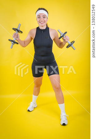 Young woman lifting dumbbells promoting fitness and strength Young woman lifting dumbbells promoting fitness and strength 138012549