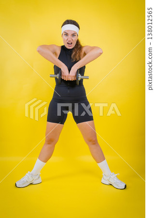 Woman exercising with dumbbell showing strength and effort 138012565