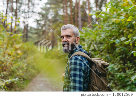 Handsome man standing in the middle of nature, enjoying peaceful atmosphere of the forest, forestbathing. Handsome man standing in the middle of nature, enjoying peaceful atmosphere of the forest, forestbathing. 138012569