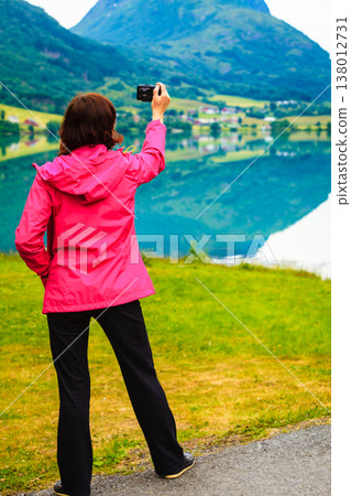 Tourist taking photo at norwegian fjord lake Tourist taking photo at norwegian fjord lake 138012731