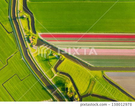 Traditional Dutch windmill stands by a calm canal. Symmetrical rows 138012978