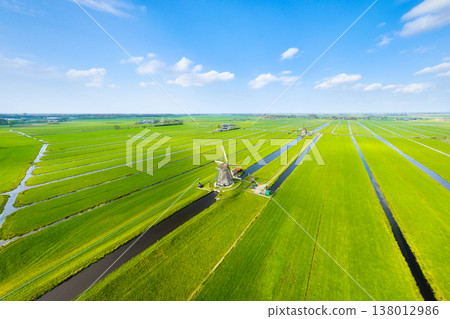 Aerial view of traditional Dutch windmills by water canals in a green field. Aerial view of traditional Dutch windmills by water canals in a green field. 138012986