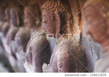 Row of ancient weathered Buddha statues in Wat Umong cave temple in Chiang Mai 138013076