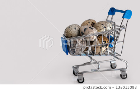 Mini shopping cart filled with speckled quail eggs on white background, symbolizing Easter shopping Mini shopping cart filled with speckled quail eggs on white background, symbolizing Easter shopping 138013098