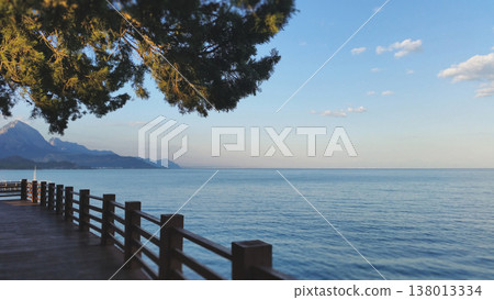 Scenic view of a wooden pier along the blue sea with mountains in the background Scenic view of a wooden pier along the blue sea with mountains in the background 138013334