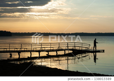 silhouette of a fisherman at sunset on the lake 138013389