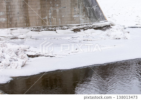 Frozen River Ice Along Concrete Bridge Foundation In Winter Frozen River Ice Along Concrete Bridge Foundation In Winter 138013473
