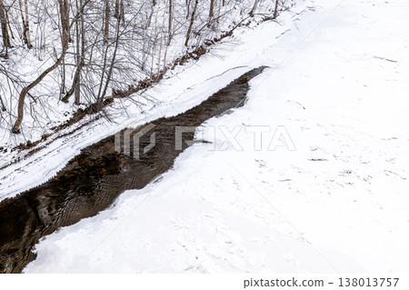 Partially Frozen Stream Cutting Through Snow Covered Winter Forest Partially Frozen Stream Cutting Through Snow Covered Winter Forest 138013757
